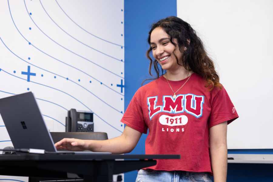 A student presents on a computer at the front of an LMU classroom.